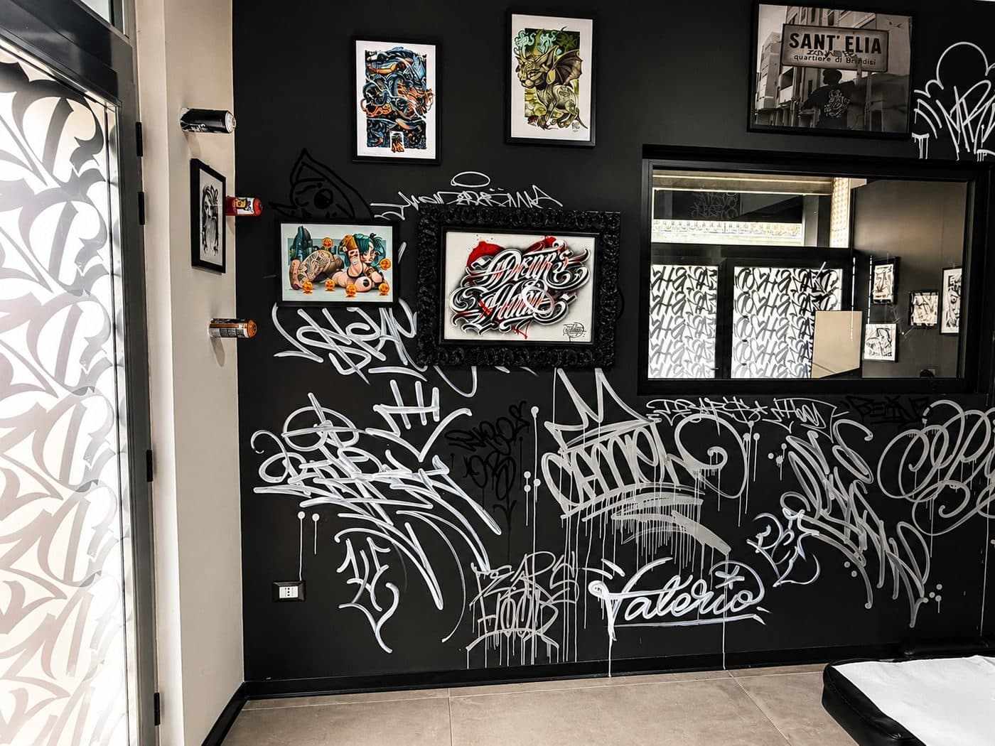 Parete graffiti con opere incorniciate dello studio DEAR'S HOOD